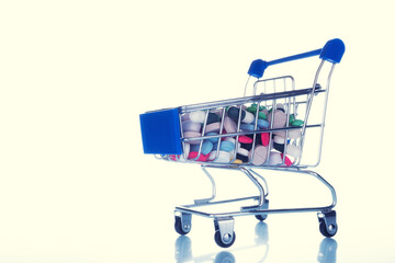 medical pills in a grocery basket on white yellow background. concept of expensive medicines