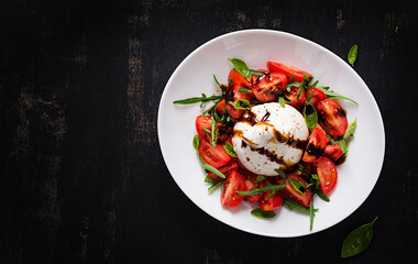 Salad with tomatoes and burrata cheese with basil and olive oil on plate. Italian food. Top view, flat lay