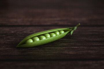 fresh pea pod open with peas on a wooden background