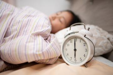 眠る子供の枕元にある目覚まし時計