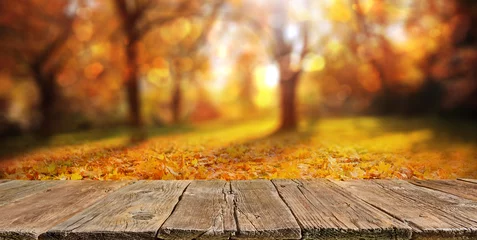 Poster Wooden table with orange leaves autumn background © andreusK