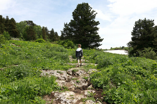 Child walking along path that crosses meadow on Lago-Naki plateau