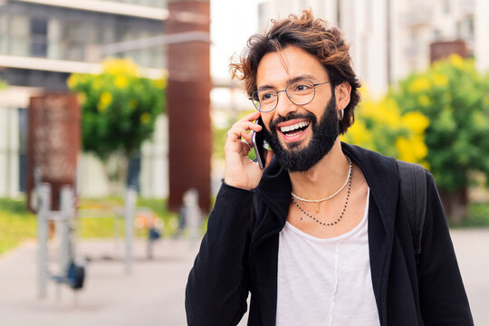 stylish young man with smiling happy while talking on mobile phone in the city, concept of urban lifestyle and technology of communication, copy space for text