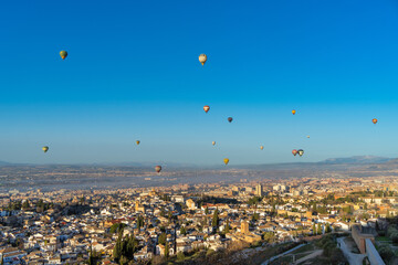 hot air balloons fly over the city in the blue sky