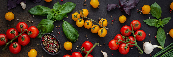 Food banner, fresh ripe red and yellow tomatoes, spices and basil leaves, garlic and green onions on a dark board, healthy food concept, top view