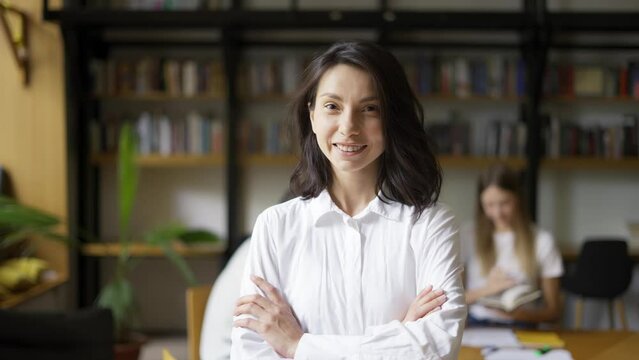 Positive cute girl with black hair wearing shirt student or teacher looking at camera smiling friendly