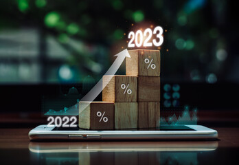 Shining rise up arrow on wood blocks chart steps with percentage icons and graph from year 2022 to...
