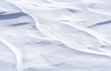 Freshly fallen snow surface looking like dunes shaped by wind. Winter abstract snow texture background.
