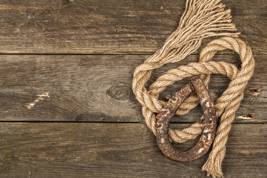 Horseshoe and vintage rope. Concept of good luck for St. Patrick's Day. Old wooden boards background
