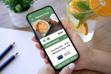 female hands holding phone with food delivery application on screen