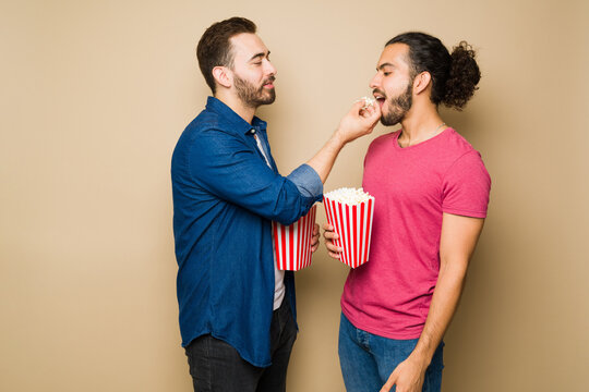 Young Caucasian Man Eating Popcorn With His Boyfriend At The Movies