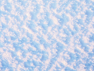 Natural snow texture. The surface of an icy snow crust. Snowy ground. Winter background with snow patterns. Perfect for Christmas and New Year design. Closeup top view.