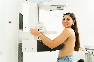 Portrait of a happy hispanic woman at the imaging diagnostic lab smiling while getting a mammogram...