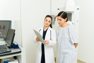 Caucasian doctor checking the test results with a young woman after doing a mammogram - obrazy, fototapety, plakaty