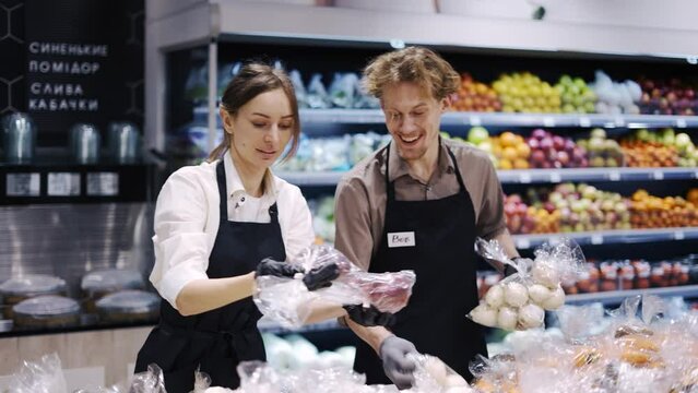 Happy workers in a black apron sort products and put them on a rack. Work in the store. Weekdays. healthy food