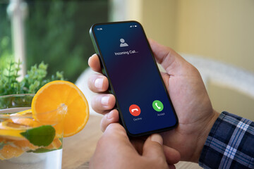 Man hands holding phone with incoming call on the screen