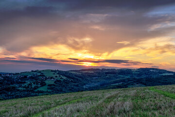 Rural hilly landscape after sunset. Countryside with field in the foreground. Beautiful sky with colorful clouds. Vlci Vrch, Slovakia.