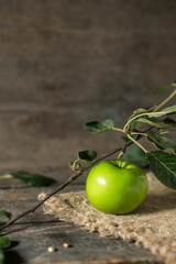 Green apple with leaves on burlap on wooden boards