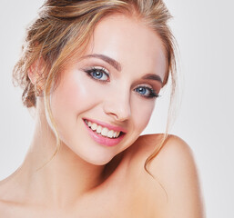 Studio shot of a beautiful young woman with perfect skin against a gray background.