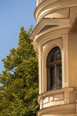 Yellow building with windows and blue sky and green tree next to it