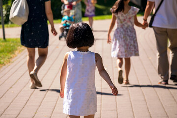 Multiple people walking on the road next to the green grass
