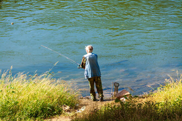 An old man is fishing, a fisherman, spending time in nature.