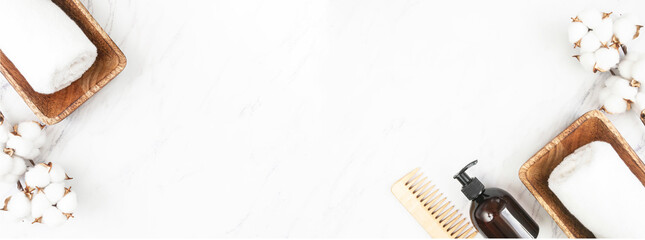 Cosmetic bottle container for shampoo and conditioner for hair, towels, wooden hair comb on marble background banner