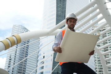 Architect or engineer with blueprints. Cauacsian Engineer checking plan on construction site. modern structure.