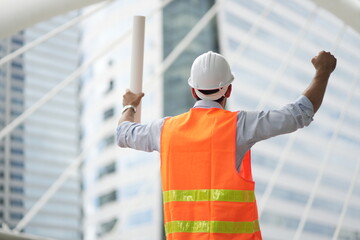 Architect or engineer with blueprints. Cauacsian Engineer checking plan on construction site. modern structure.