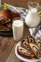 Roll with poppy seeds and a glass of milk. Food on the table. Sweet sweet pastries. Homemade simple yeast bun with filling. Breakfast on a wooden table. lactose and gluten. Honey spas