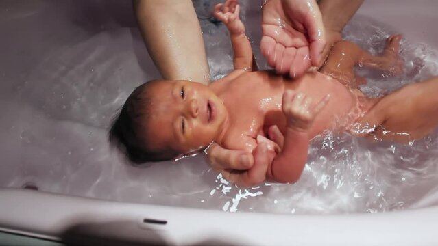 Newborn baby girl making her first bath at home