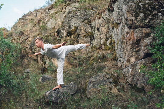 A Young Guy Is Doing Yoga Near A Rock.