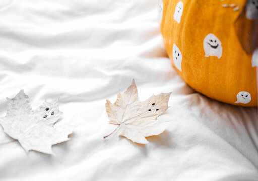 DIY funny ghosts, boo painted on leaves and pumpkin. Close up Halloween party decor. copy space, Halloween, holiday concept on white background