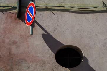 Un caretello che indica il divieto di parcheggio lascia la sua ombra su un muro colito dal sole