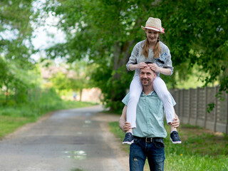 Obraz premium Caucasian father with teen girl daughter on shoulders having fun outdoor park