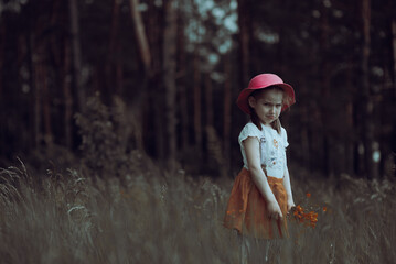 Little angry girl in a pink hat walks in a flowering summer meadow