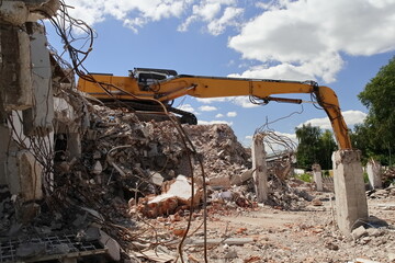 An excavator during the demolition of a building - obrazy, fototapety, plakaty