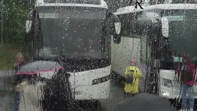 blurry image of tourists with umbrellas boarding the bus during rain
