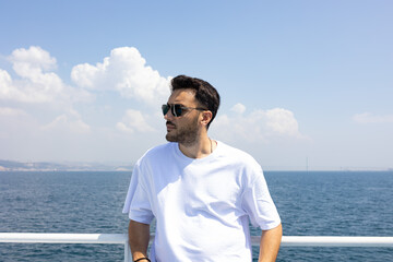 Young, handsome man with sun glasses by sea. Summer vacation, freedom and holiday concept. 