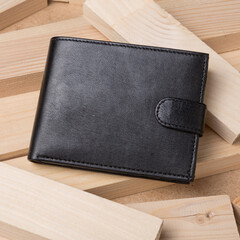 One black leather wallet on a textured wooden background from the boards