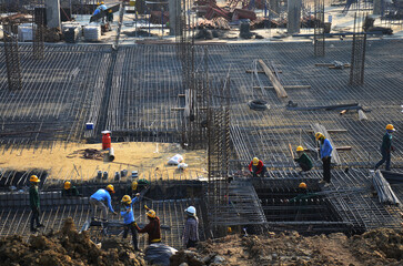 Asian labor people and thai labour worker knitting metal rods bars into framework reinforcement for concrete pouring for working new structure building at site on January 19, 2014 in Bangkok, Thailand