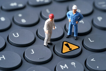 Two engineer miniature figure standing to analysis with yellow exclamation caution warning mark...