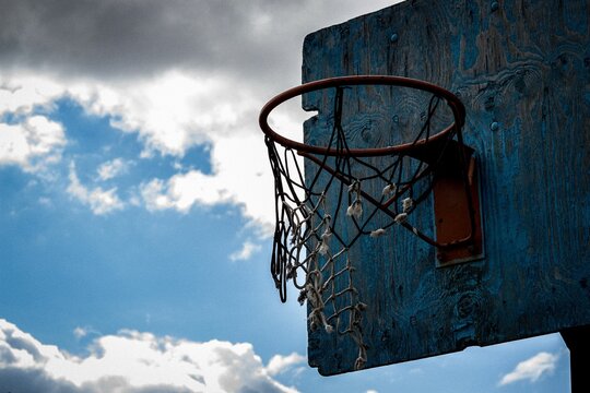 Low Angle Shot Of The Backboard In An Empty Basketball Park With A Damaged Old Net And Hoop