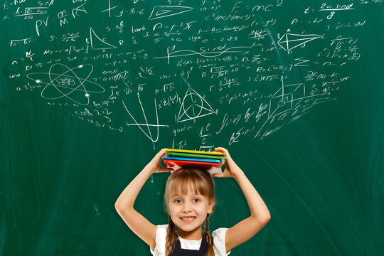 Kids math education concept. Cute little girl mathematics student on school background with hand drawings science formula pattern.