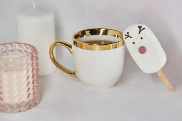 Festive afternoon tea with white cup, cute marshmallow deer, gingerbread cookie and pink candle. Aesthetic tea time. Christmas inspiration concept. Good morning or cozy home concept.