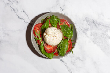 salad of fresh tomatoes, herbs and burrata cheese on a gray background