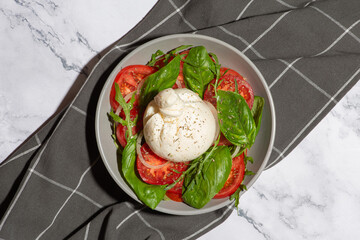 salad of fresh tomatoes, herbs and burrata cheese on a gray background