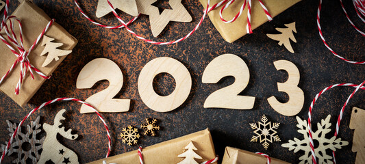Happy new year 2023. Wooden Christmas or new year decorations on a wooden brown background. ECO...