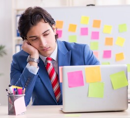 Young male handsome employee in conflicting priorities concept