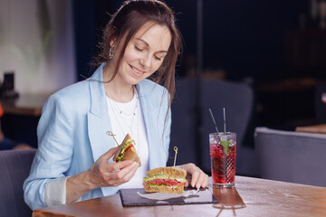 girl eating delicious sandwich close up in modern cafe